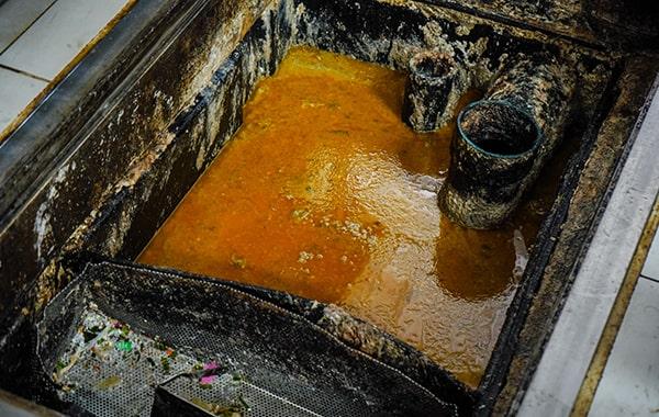 foul odors, slow drainage, and visible grease buildup are all signs that your grease trap might need cleaning